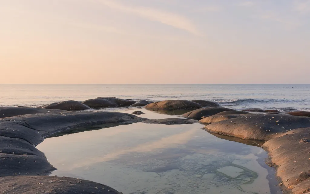 A cluster of calm tide pools on a quiet shore at soft morning light