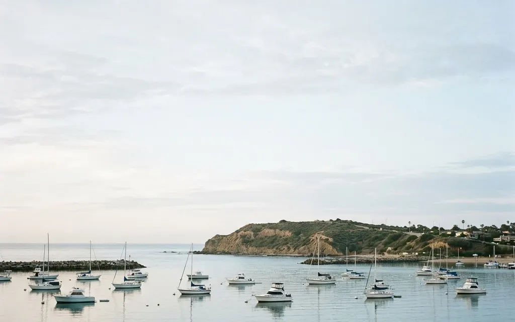 Calm Newport Beach harbor and headland at soft morning light with open sky and moored boats, no people