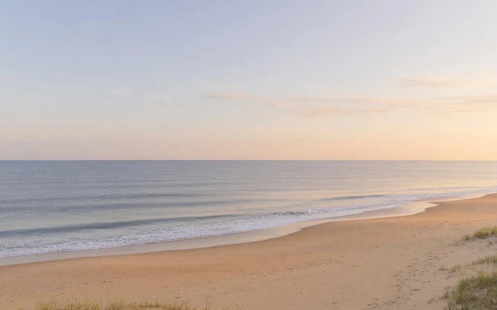 Calm wide Oceanside shoreline and gentle surf at soft morning light with open sky