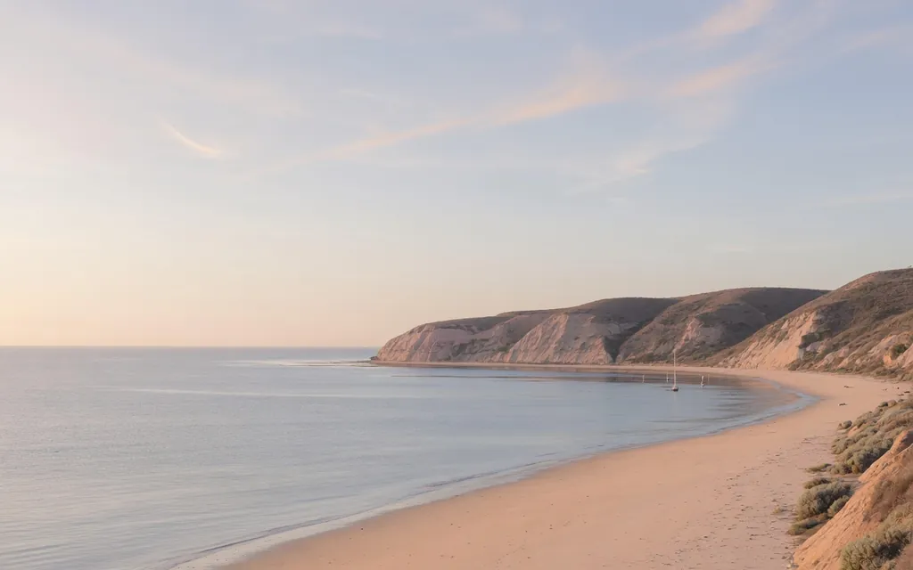 Calm San Diego County coastal bay and low bluffs under soft morning light with open sky